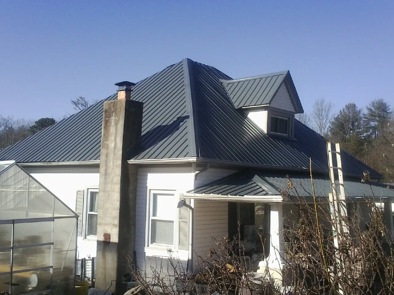 Dark blue standing seam metal roof on a white farmhouse with dormer — Slate & Tile Roof Repair by Roofing Brothers in Kershaw