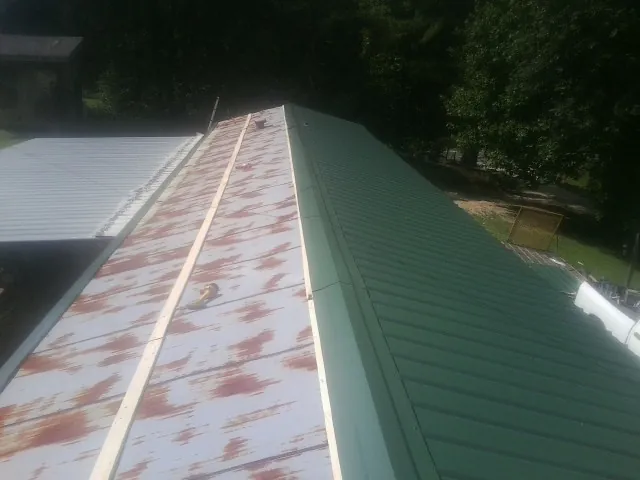 Old rusted panels beside newly installed green metal roofing — Wind Damage Roof Repair by Roofing Brothers in Kershaw