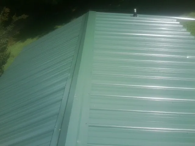 New green metal panels meeting at the ridge of a roof — Flat Roof Repair work by our crew in Kershaw