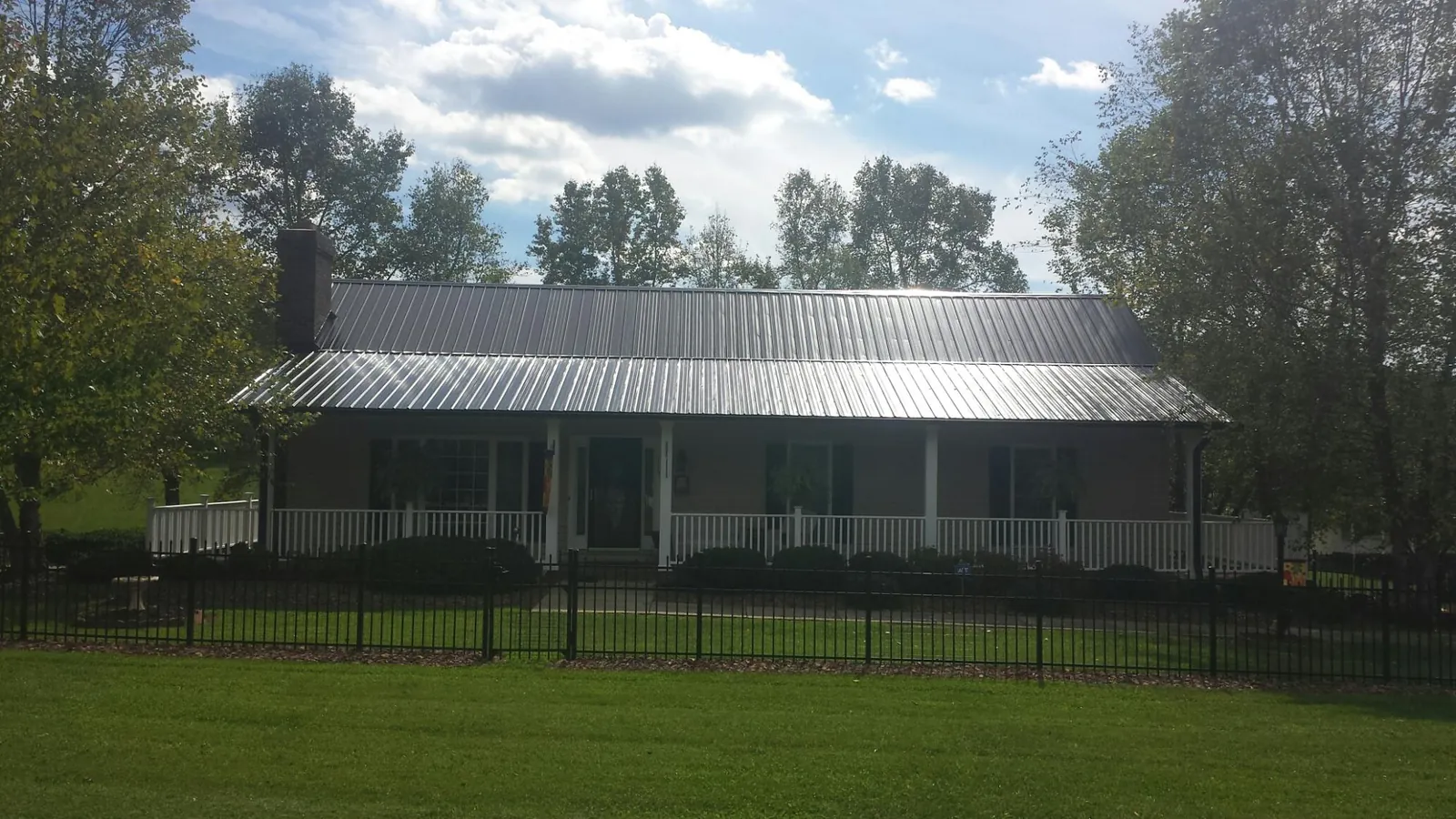 Gray metal roof on a brick ranch with a full width front porch — Gutter Guard Installation work by our crew in Kershaw