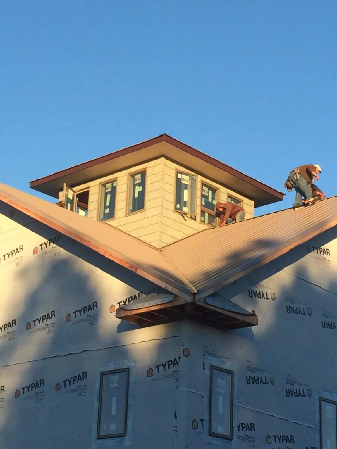 Roofers working around a rooftop cupola on a new metal roof at sunset — Roof Waterproofing in Kershaw by Roofing Brothers